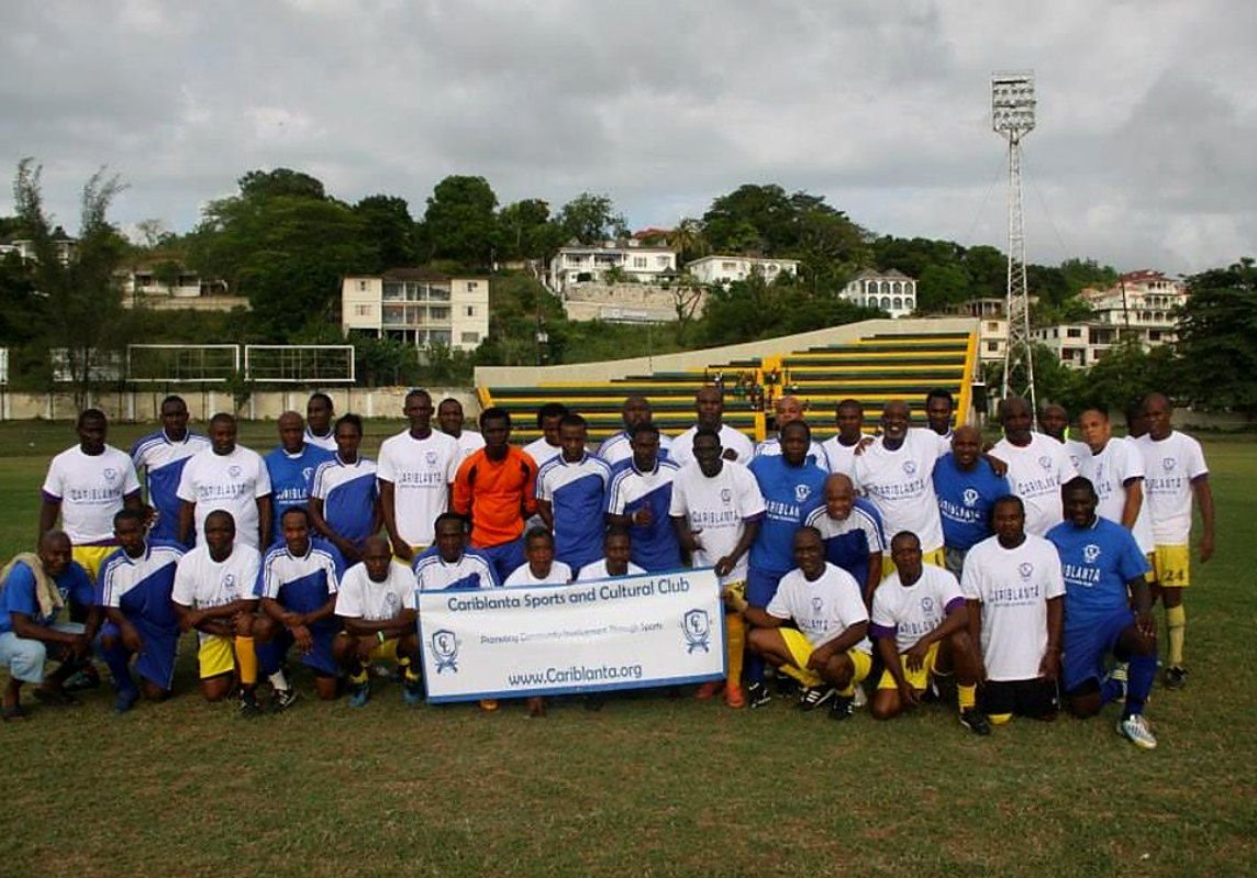 Cariblanta members in club jerseys with the Cariblanta Sports and Cultural Club banner after a match in Jamaica